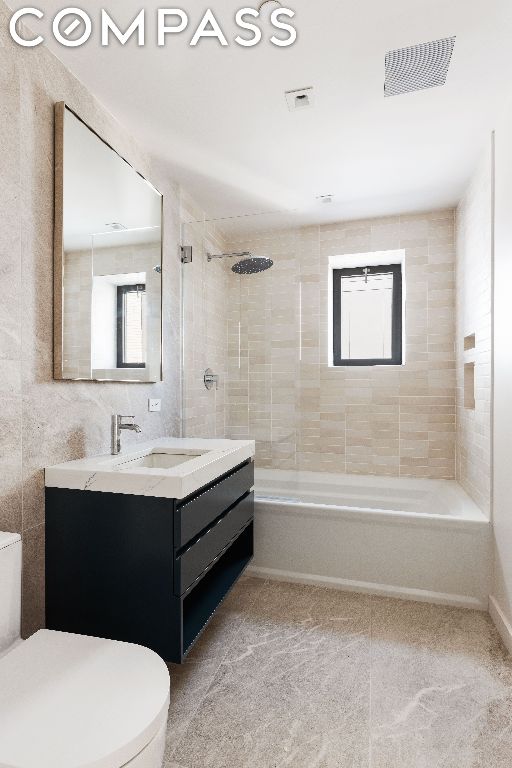 full bathroom featuring toilet, vanity, and tiled shower / bath