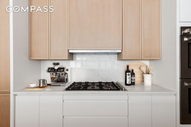 kitchen featuring under cabinet range hood, backsplash, appliances with stainless steel finishes, and light countertops