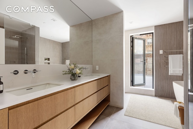 full bathroom with a sink, a healthy amount of sunlight, tile patterned floors, and a tile shower