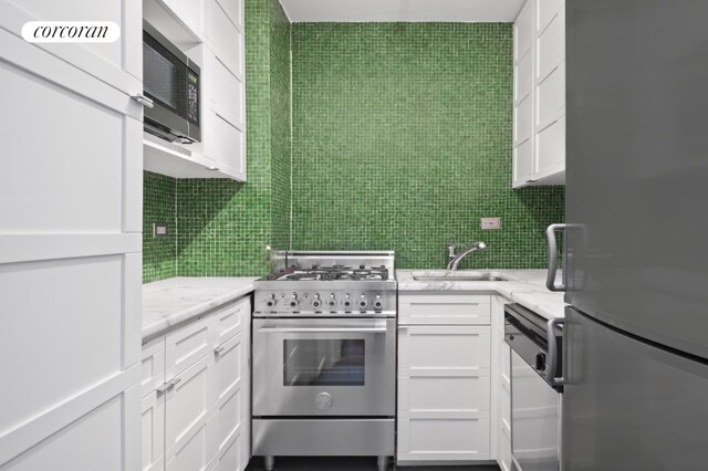 kitchen featuring white cabinetry, sink, premium appliances, and light stone countertops