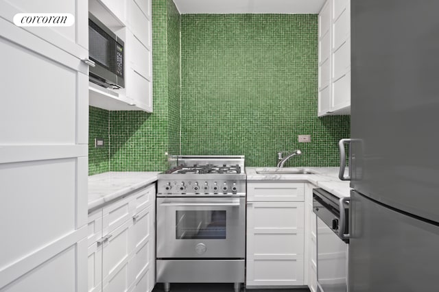 115 E 9th St Unit 6R, New York City, NY 10003 - kitchen with appliances with stainless steel finishes, a sink, white cabinetry, decorative backsplash, and tile walls
