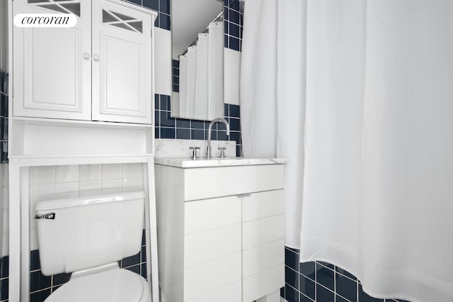 bathroom with toilet, tile walls, and vanity