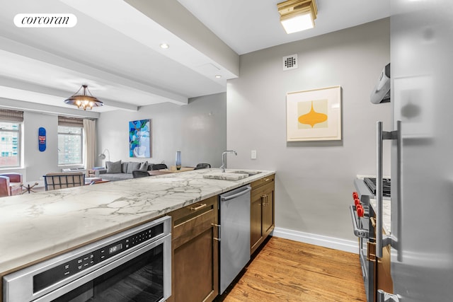 kitchen featuring visible vents, appliances with stainless steel finishes, light wood-style flooring, and a sink