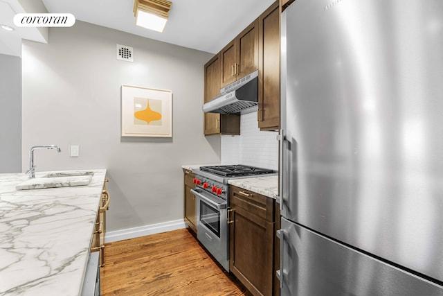 kitchen featuring visible vents, stainless steel appliances, light wood-type flooring, under cabinet range hood, and a sink