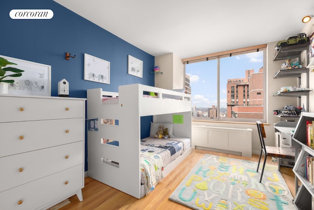 bedroom featuring a view of city and light wood finished floors