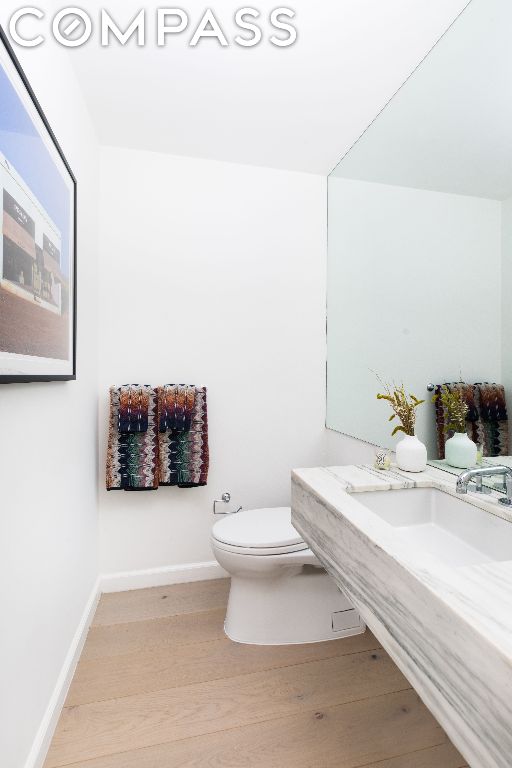 bathroom featuring vanity, toilet, wood finished floors, and baseboards