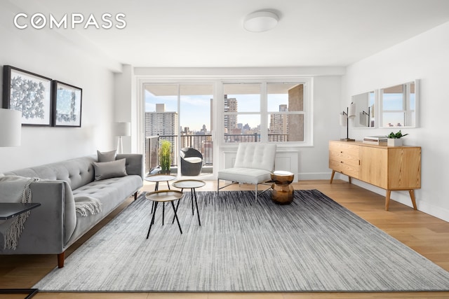 living area with baseboards, a view of city, and wood finished floors