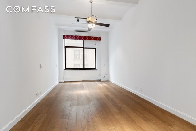 spare room featuring ceiling fan, wood-type flooring, and beam ceiling