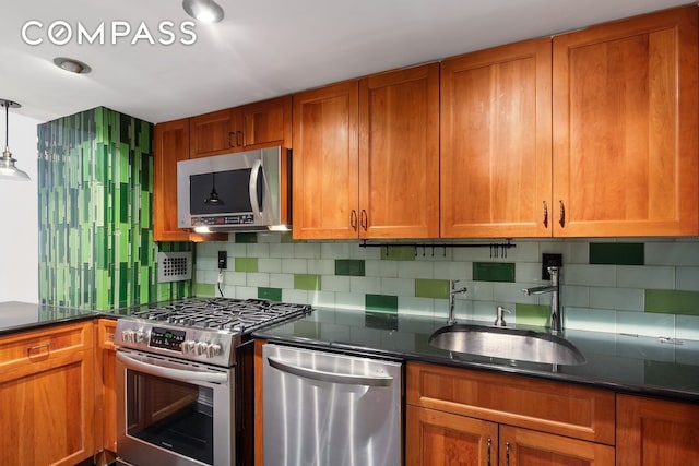 kitchen featuring brown cabinetry, appliances with stainless steel finishes, tasteful backsplash, and a sink