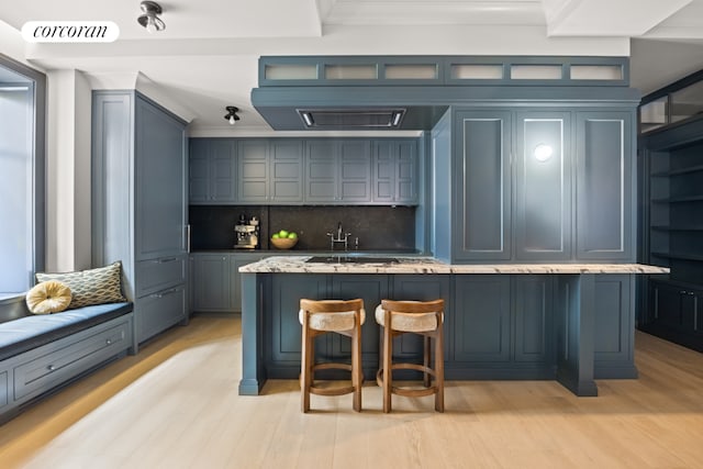 bar with light wood-type flooring, backsplash, light stone countertops, and sink