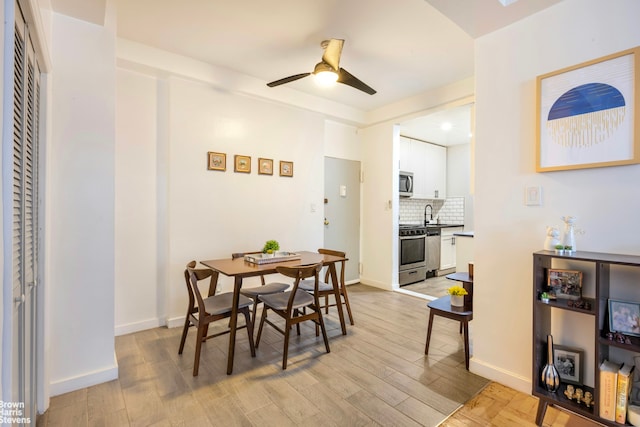 dining space featuring ceiling fan, light wood-type flooring, and baseboards