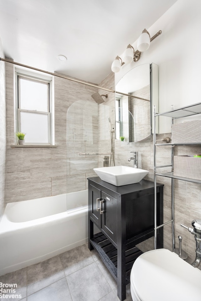 bathroom featuring tile walls, tile patterned floors, vanity, toilet, and shower / tub combination