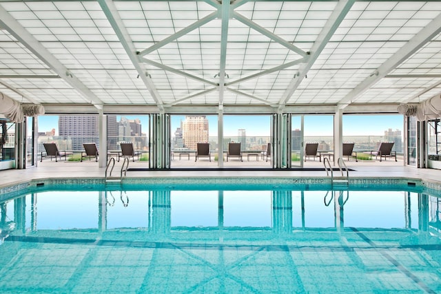 indoor community pool with a patio, fence, and a city view