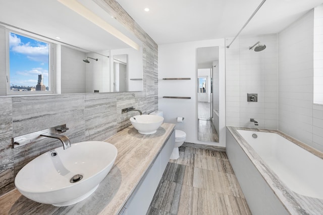 full bath featuring tile walls, toilet, and double vanity