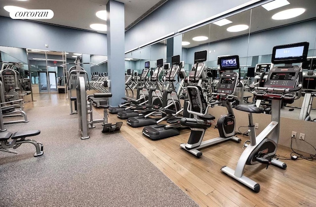 gym featuring wood-type flooring and a towering ceiling