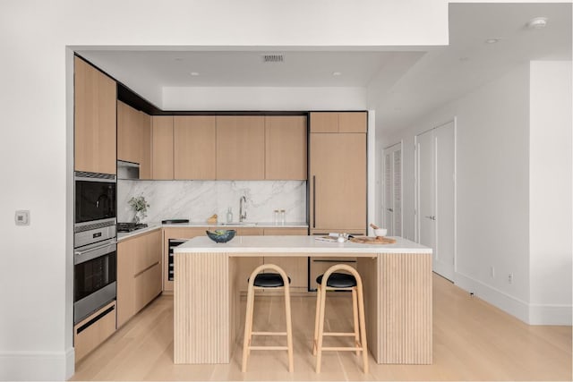 kitchen with appliances with stainless steel finishes, a kitchen island with sink, a breakfast bar area, and decorative backsplash