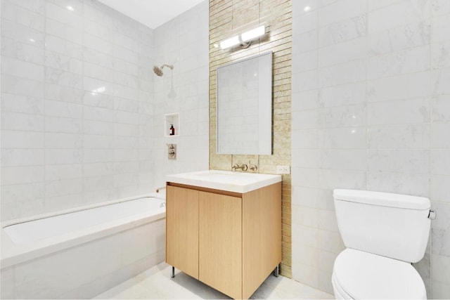 full bathroom featuring tile walls, vanity, tiled shower / bath, and toilet