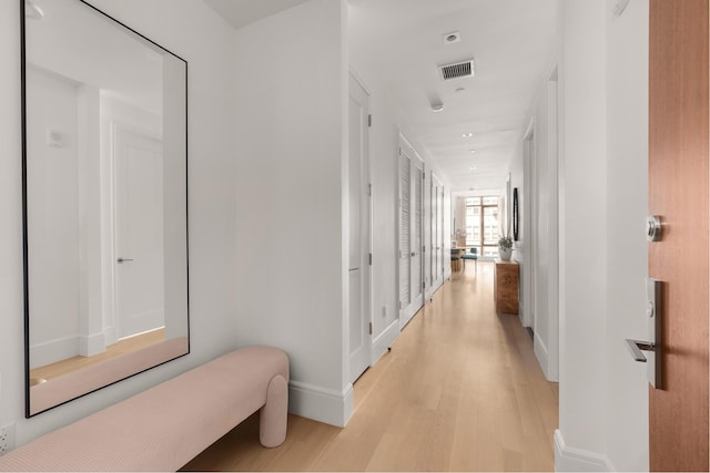 corridor featuring visible vents, baseboards, and light wood-style floors