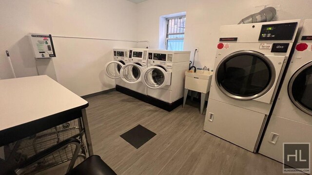 shared laundry area with wood finished floors, separate washer and dryer, and a sink