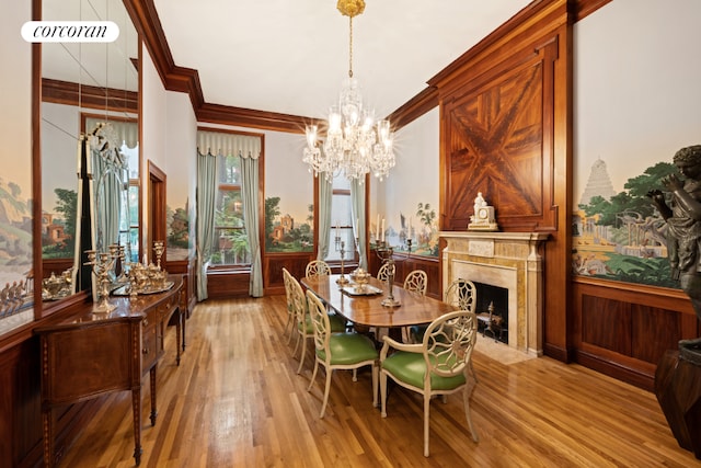 dining room with a fireplace, ornamental molding, a notable chandelier, and light wood-type flooring