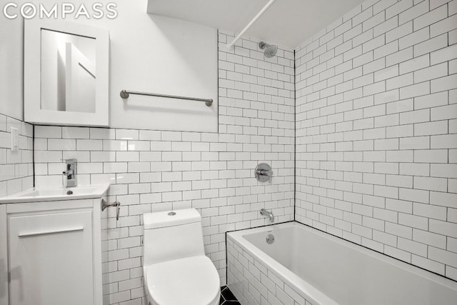 full bathroom featuring tiled shower / bath, tile walls, vanity, and toilet