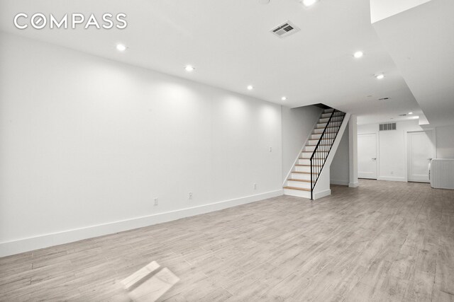 clothes washing area featuring stacked washer and clothes dryer, sink, and light hardwood / wood-style flooring