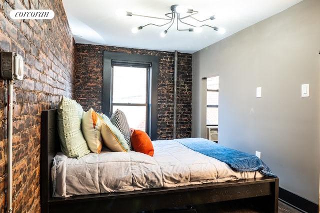 bedroom with a notable chandelier and brick wall