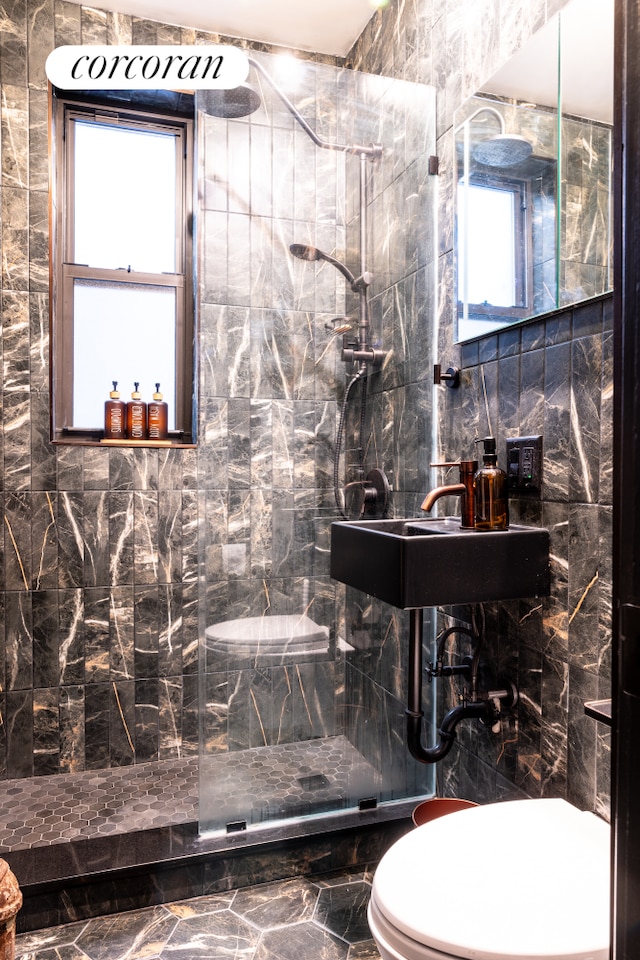 bathroom featuring a sink, toilet, tile walls, and a walk in shower