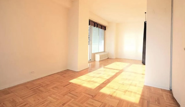 spare room featuring light parquet floors and radiator