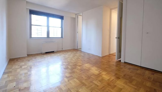 unfurnished room featuring radiator heating unit and light parquet flooring