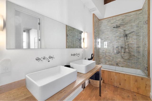 bathroom with wood-type flooring, shower / bath combination with glass door, and vanity