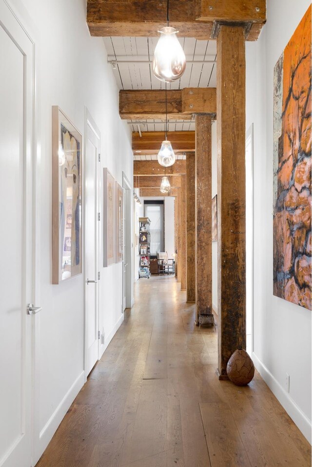 hall with wood ceiling, baseboards, beam ceiling, wood-type flooring, and decorative columns