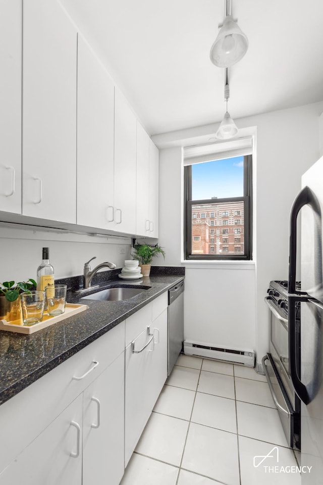 kitchen with a baseboard radiator, appliances with stainless steel finishes, white cabinets, and a sink