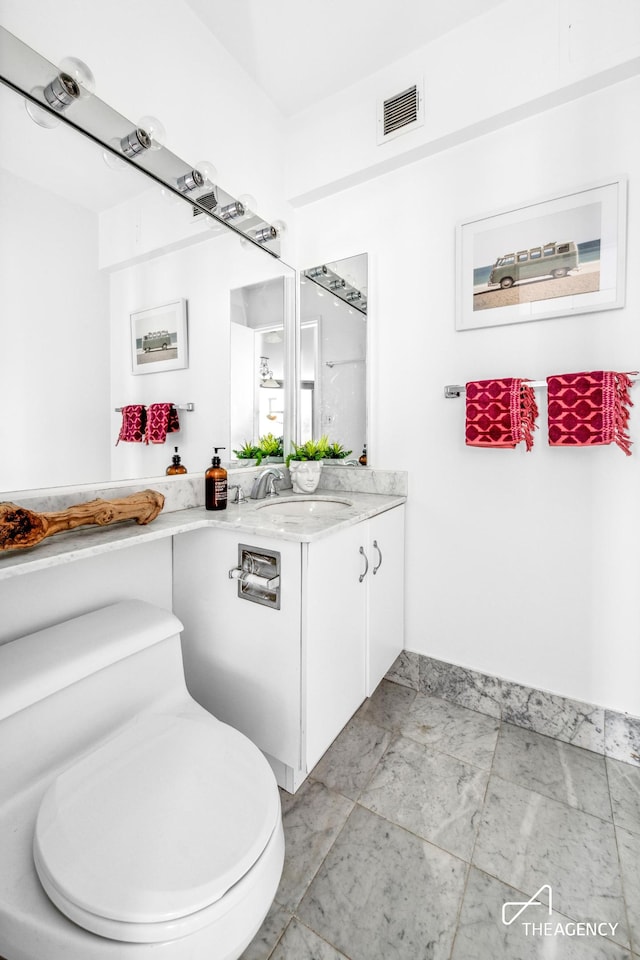 bathroom with toilet, vanity, visible vents, and baseboards