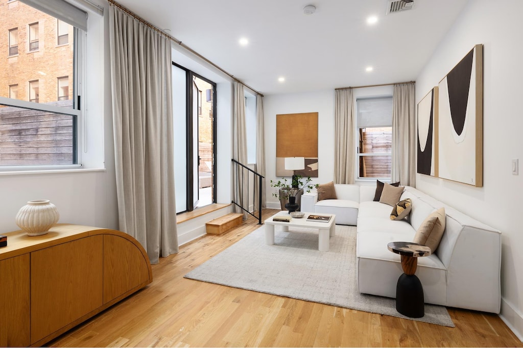 living room featuring recessed lighting, visible vents, wood finished floors, and stairway