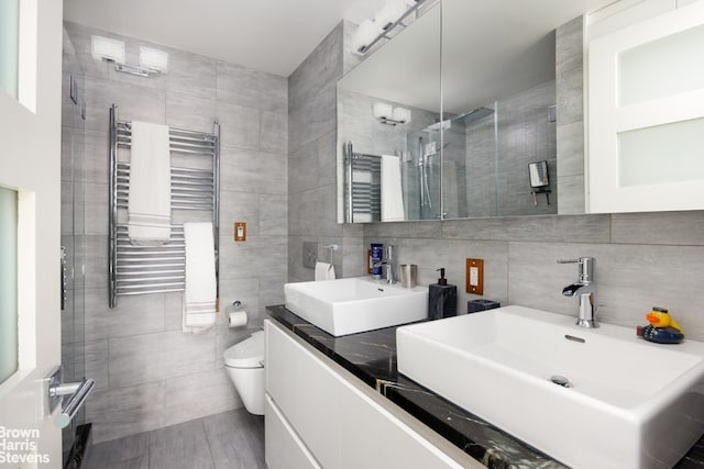 175 W 95th St Unit 2C, New York City, NY 10025 - full bathroom with radiator heating unit, tile walls, a towel warming rack, double vanity, and a stall shower