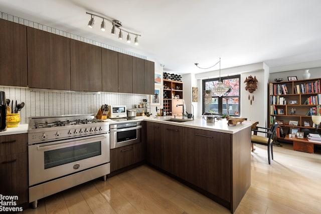 kitchen featuring dark brown cabinets, hanging light fixtures, appliances with stainless steel finishes, kitchen peninsula, and light hardwood / wood-style floors