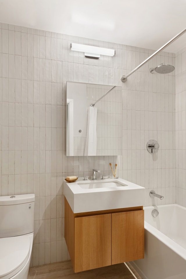 bathroom with toilet, tub / shower combination, vanity, and tile walls