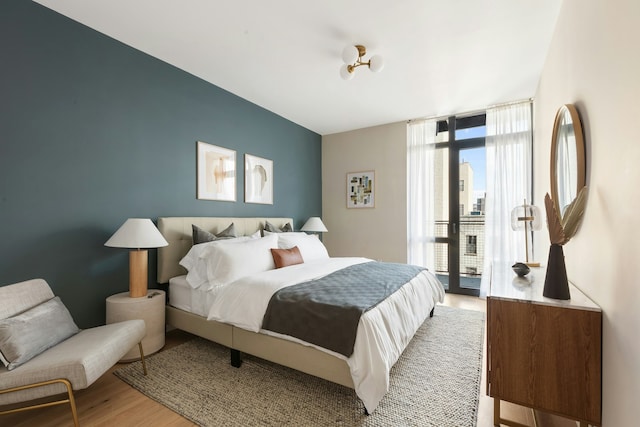 bedroom featuring access to outside, expansive windows, and wood finished floors