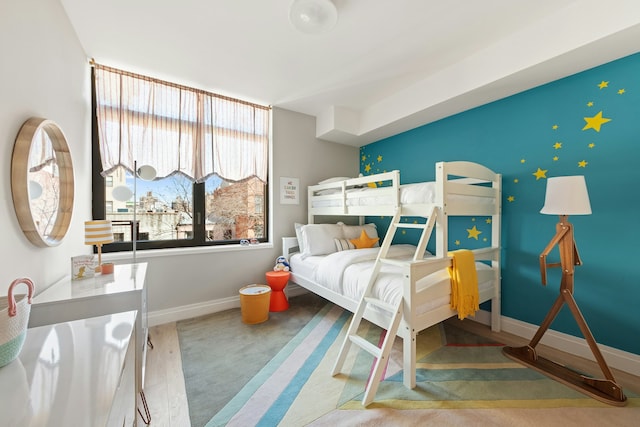 bedroom featuring baseboards, an accent wall, and carpet flooring