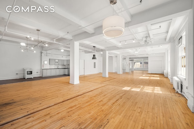 118 E 25th St Unit 8, New York City, NY 10010 - unfurnished living room featuring light wood finished floors, heating unit, beam ceiling, radiator heating unit, and baseboards