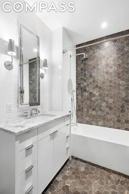 bathroom with vanity, shower / washtub combination, and tile walls