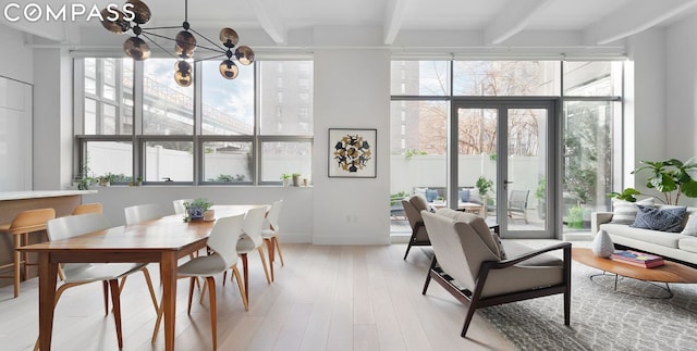 interior space with french doors, a notable chandelier, beam ceiling, and light hardwood / wood-style floors