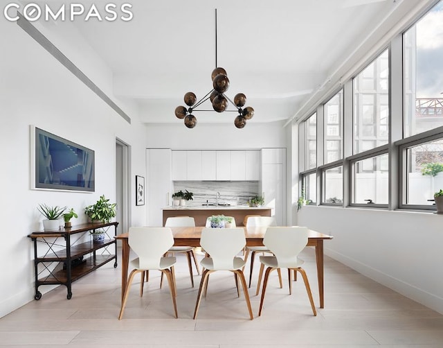 dining room with sink, a chandelier, and light wood-type flooring