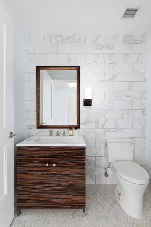 bathroom featuring vanity, tile patterned flooring, toilet, and tile walls