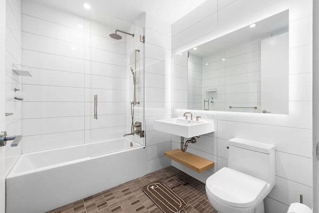 bathroom with tile patterned flooring, tile walls, toilet, and tiled shower / bath