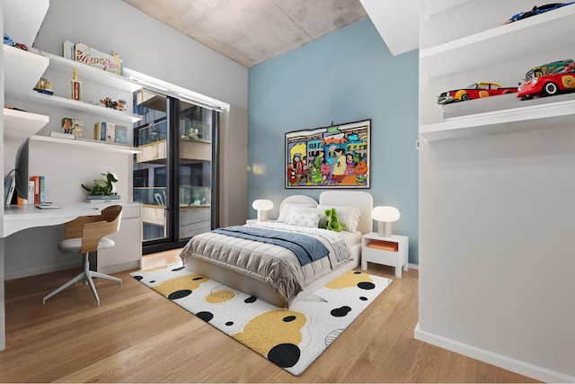 bedroom featuring light hardwood / wood-style floors, access to outside, and built in desk