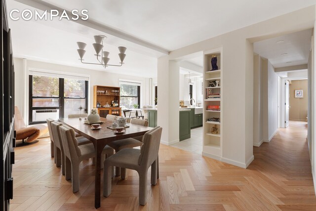 dining room with sink, a chandelier, and light parquet floors