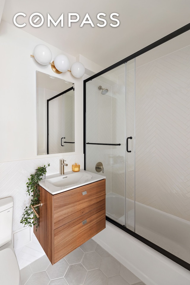 full bathroom featuring toilet, tile patterned flooring, tile walls, and vanity