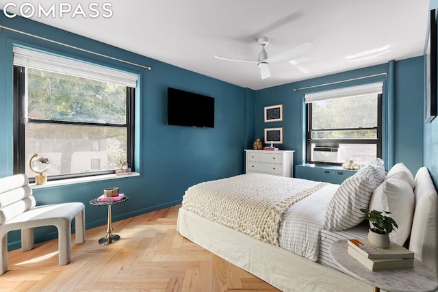 bedroom with light parquet floors, ceiling fan, and multiple windows